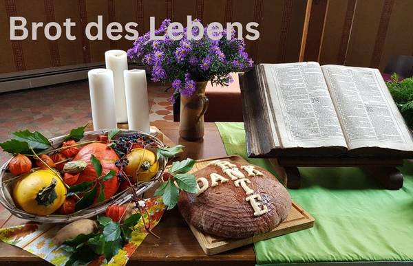 Früchte in einem Korb, Brot, Blumen und Bibel liegen zu Erntedank auf dem Altar